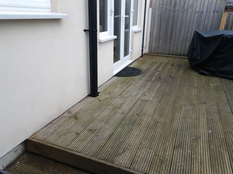 Wooden decking outside house with potential damp issues underneath.