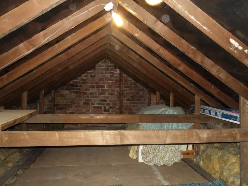 Loft space inspection showing wooden beams and insulation in a residential property.