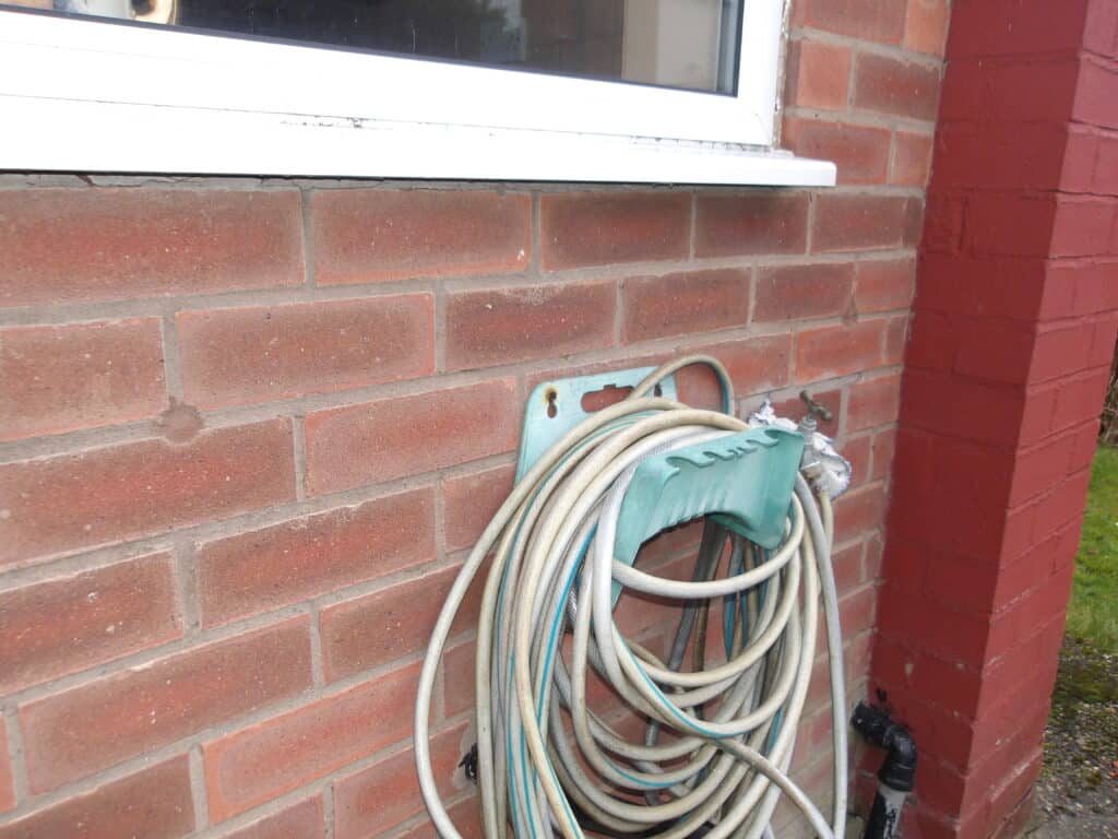 Inspection of cavity wall insulation problems outside a brick house.