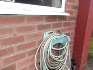 Inspection of cavity wall insulation problems outside a brick house.