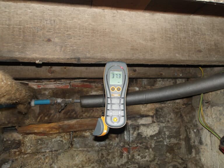 Moisture meter measuring dampness on a timber joist for survey purposes.